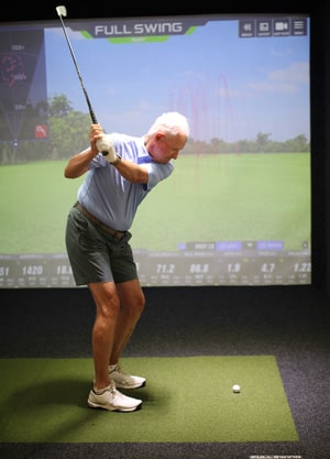 Hideaway Beach Club Member using the indoor golf simulator