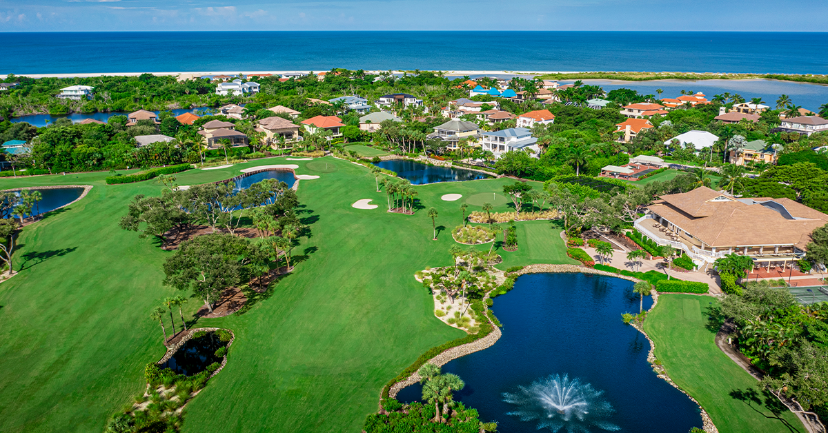 Aerial view of Hideaway Beach Club golf course with lakes, greenery, and Gulf of Mexico coastline.