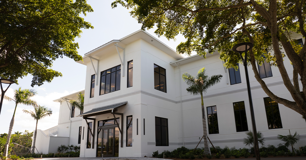 Exterior view of Hideaway Beach Club’s Sports & Wellness Center surrounded by palm trees and landscaping.