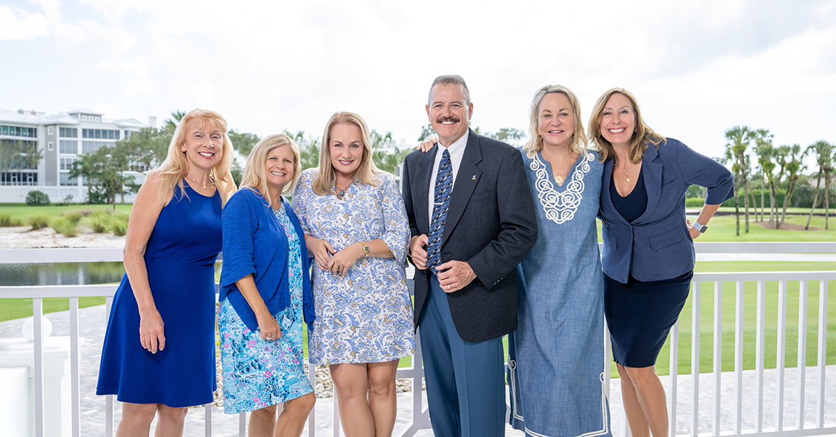 Group photo of the Michelle Thomas Team standing on a balcony overlooking a golf course.