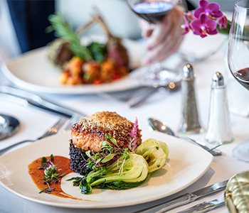 Seafood entrée plated with vegetables on a white tablecloth.