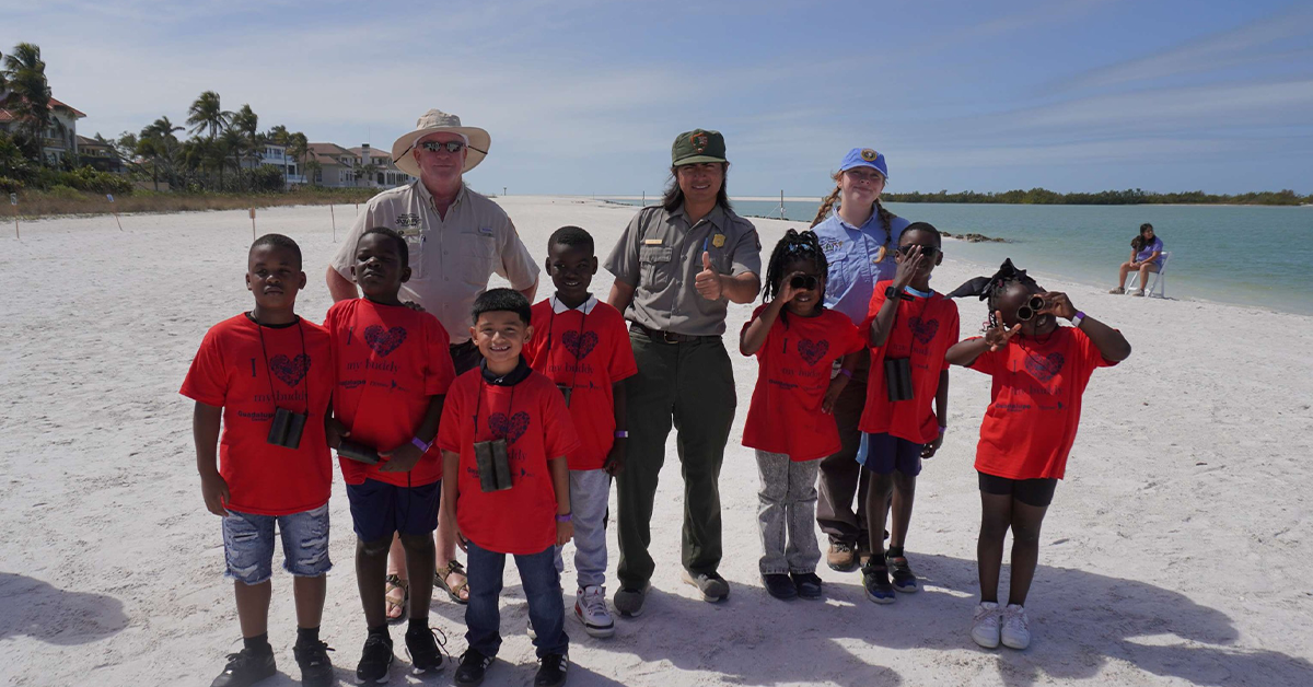Children in red shirts with park rangers on beach