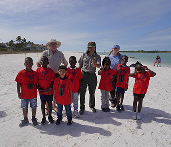 Children in red shirts with park rangers on beach