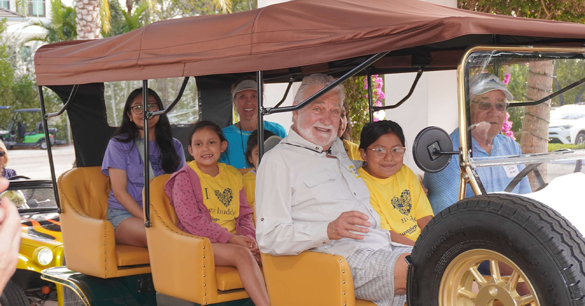 Adults and children seated in open-air vintage vehicle