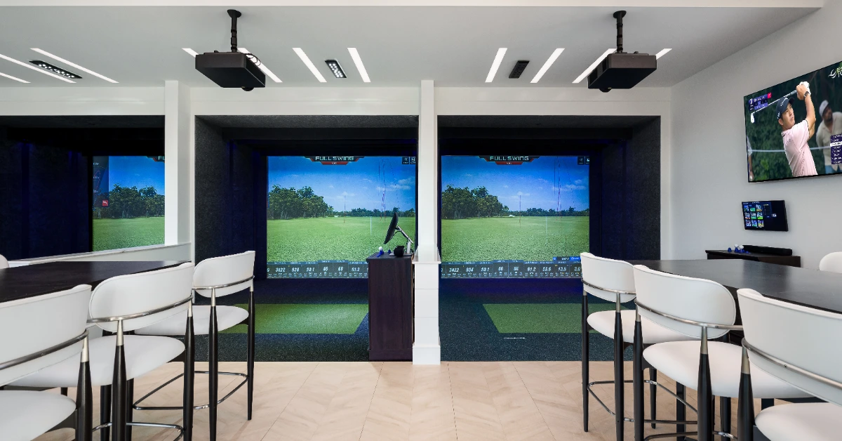 Indoor golf simulator room with screens and seating