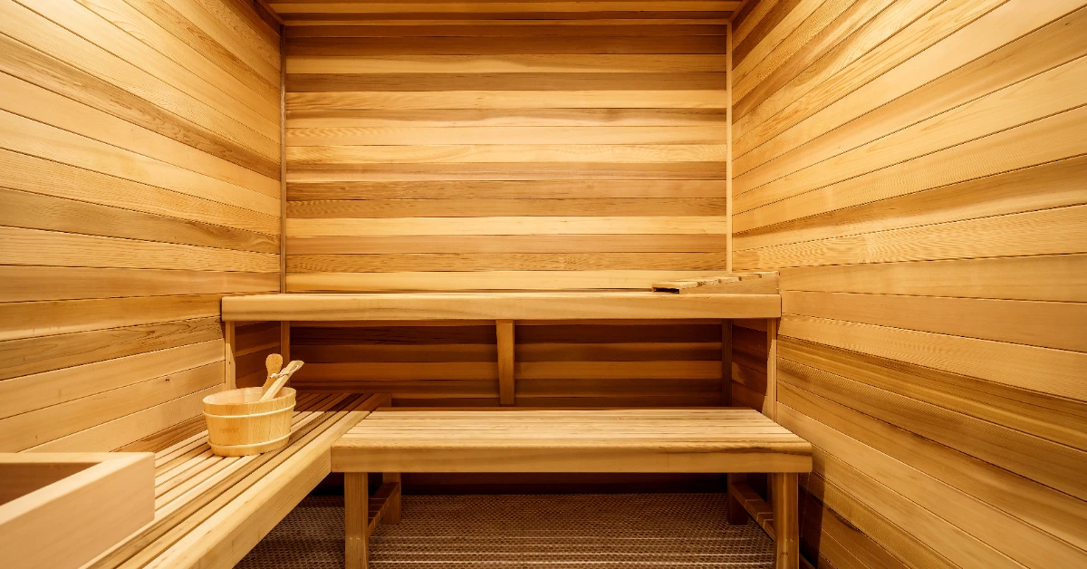 Cedar sauna interior with wooden benches and bucket