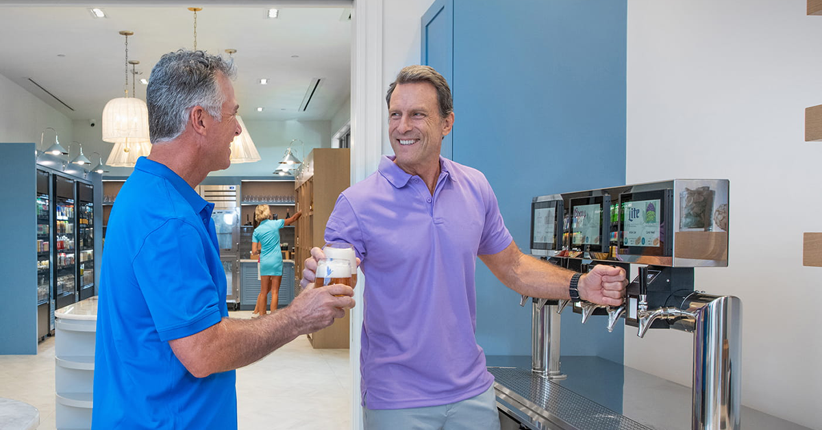 Two men pouring draft beer at clubhouse bar counter.